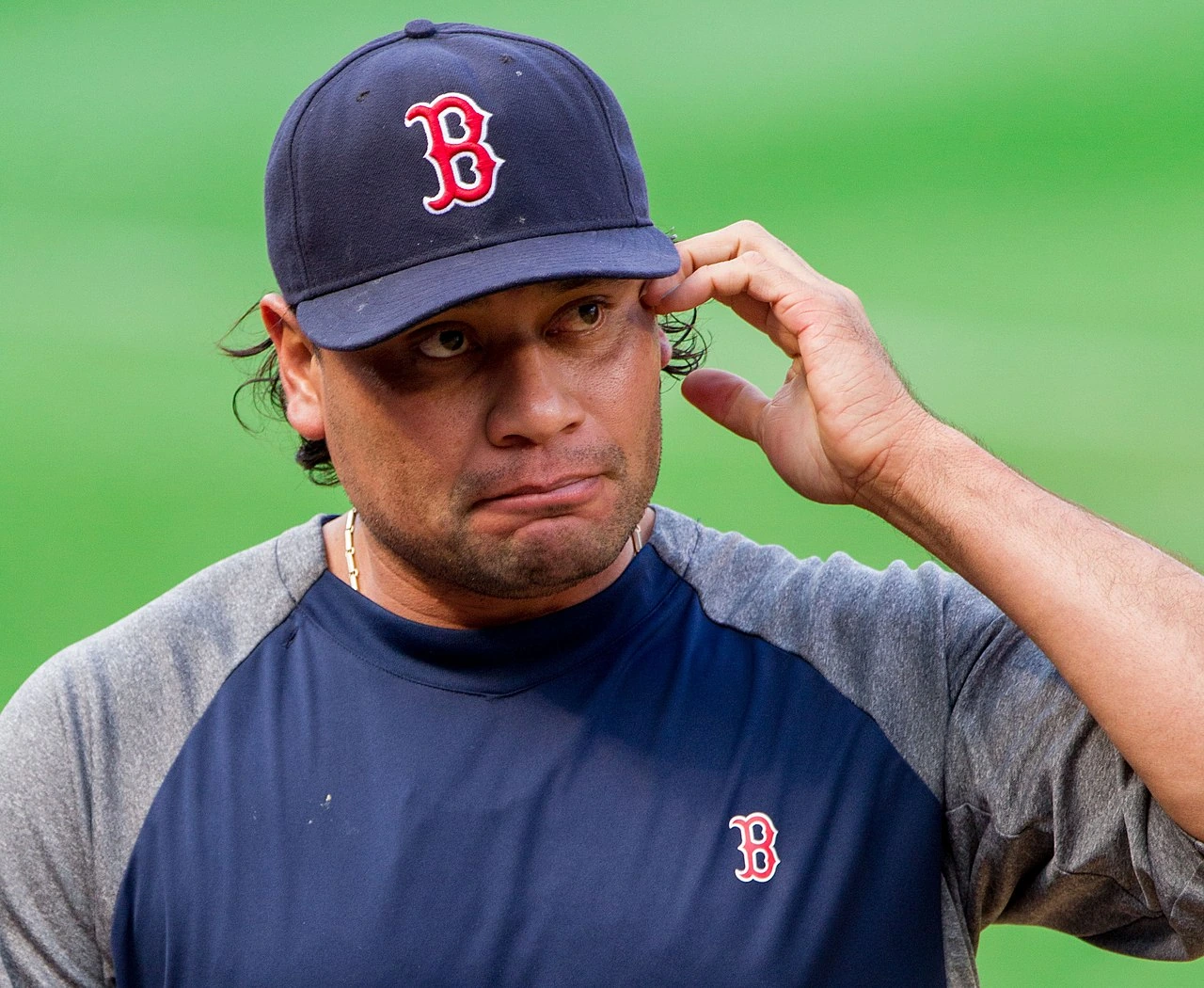 Vicente Padilla in a Boston Red Sox cap and training top, touching the side of his head